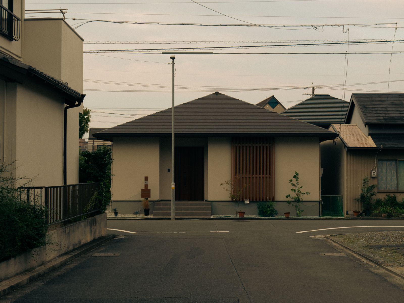 夕暮れの住宅街に建つ、瓦屋根の平屋
